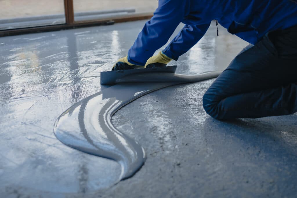 The worker applies gray polyurea to the new floor
