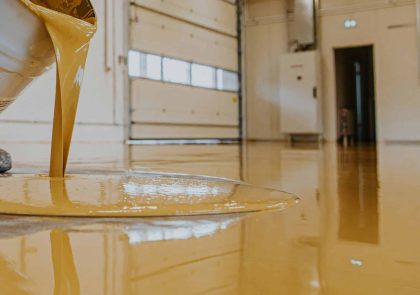 Worker, coating floor with self-leveling epoxy resin in industri
